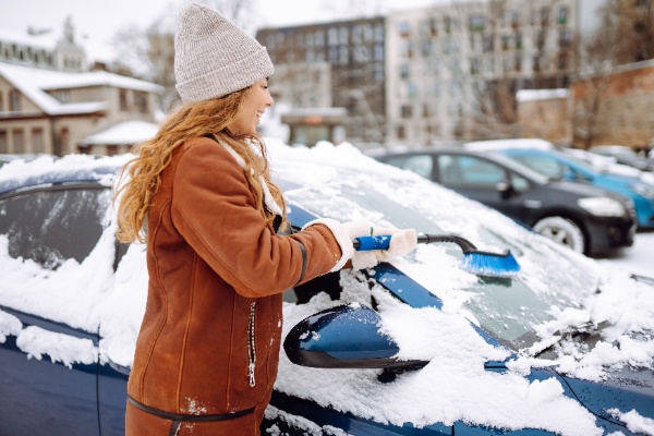 Kobieta czyści samochód ze śniegu