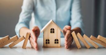 Kobieta osłaniające drewniany domek rękoma 