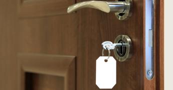 Zbliżenie na klamkę drzwi i zamek z włożonym do niego kluczem