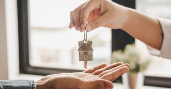 Dwie dłonie. Kobieca trzyma klucz, a męska jest podłożona pod nią.