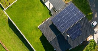 Widok na dom z lotu ptaka. Na dachu panele fotowoltaiczne.