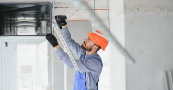 Technik montujący rekuperator na suficie.