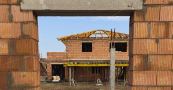 Otwór na okno z widokiem na dom w budowie.