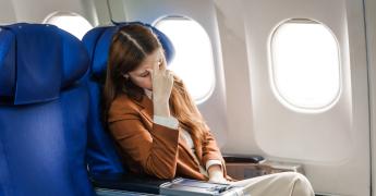 Kobieta w samolocie. Zakrywa twarz.