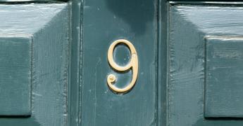 Numer 9 na tle zielonych drzwi.