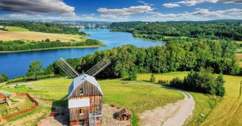 Wiatrak na tle zbiornika wodnego.