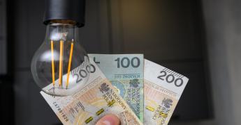 Żarówka na tle banknotów.