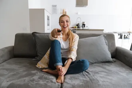 Kobieta celująca przed siebie pilotem do telewizora