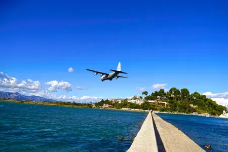 Samolot lecący nad wodą na tle wyspy.